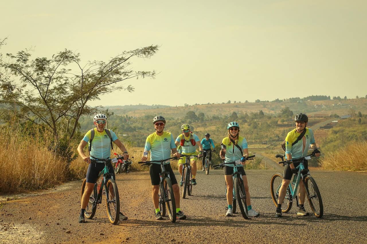 Cyclists riding from Angkor Wat to Bangkok through scenic countryside, rural villages, rice fields, and quiet backroads on a cross-border cycling tour.
