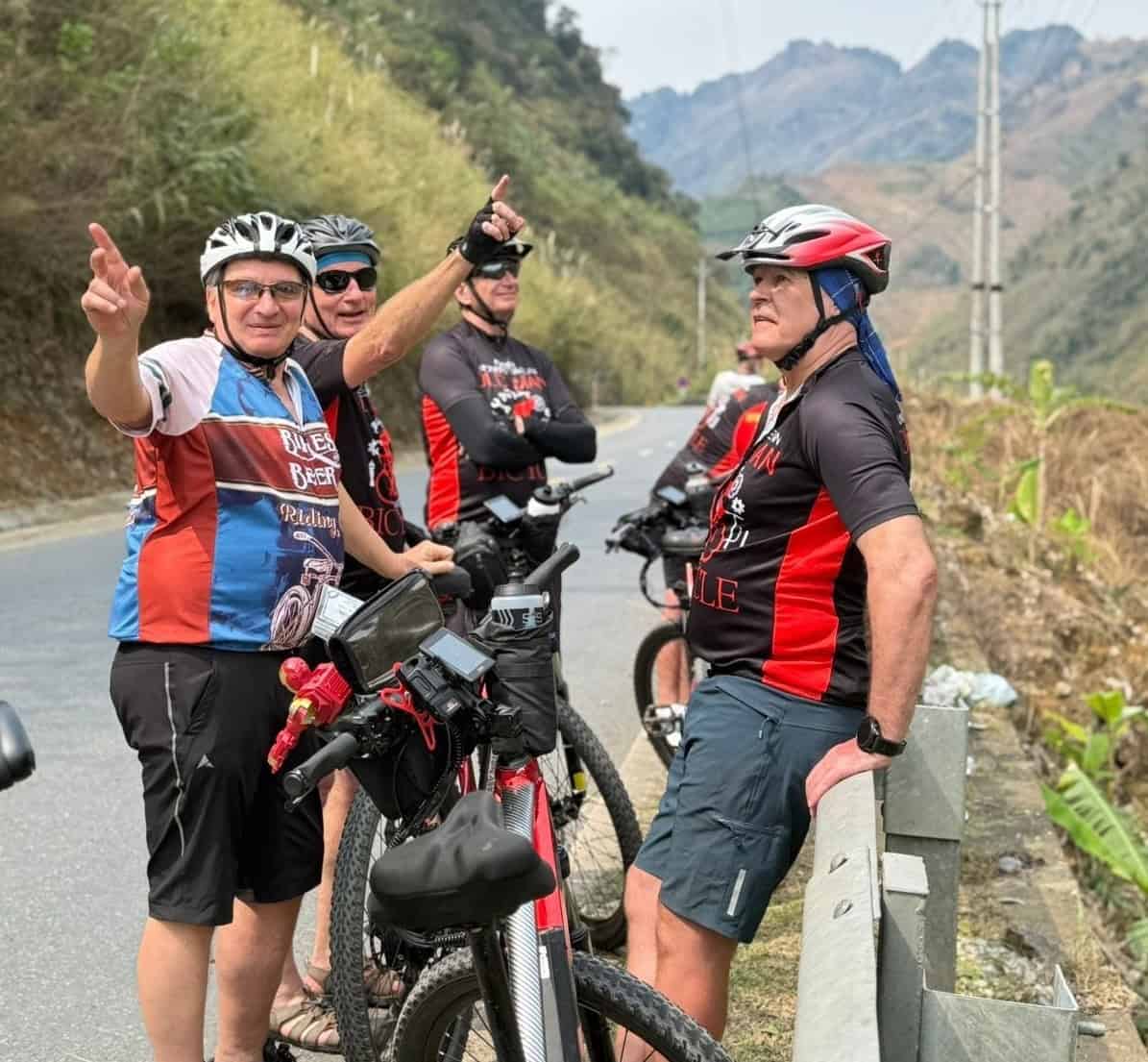 Cyclists riding through the remote mountains and countryside of northern Laos on a backroad cycling tour from Luang Prabang to Cambodia, passing traditional villages and scenic landscapes.