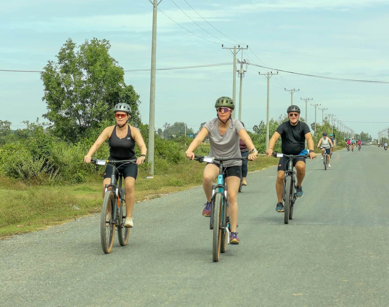 Cyclists on a rural Cambodia bike tour riding backroads between Siem Reap and Phnom Penh, passing rice fields, Khmer villages, and peaceful countryside landscapes.