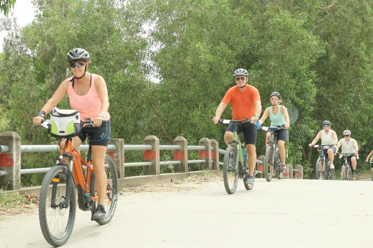 Cyclists on a Cambodia bike tour traveling from Siem Reap to Phnom Penh through rural backroads, rice fields, and traditional Khmer villages on a countryside cycling adventure.
