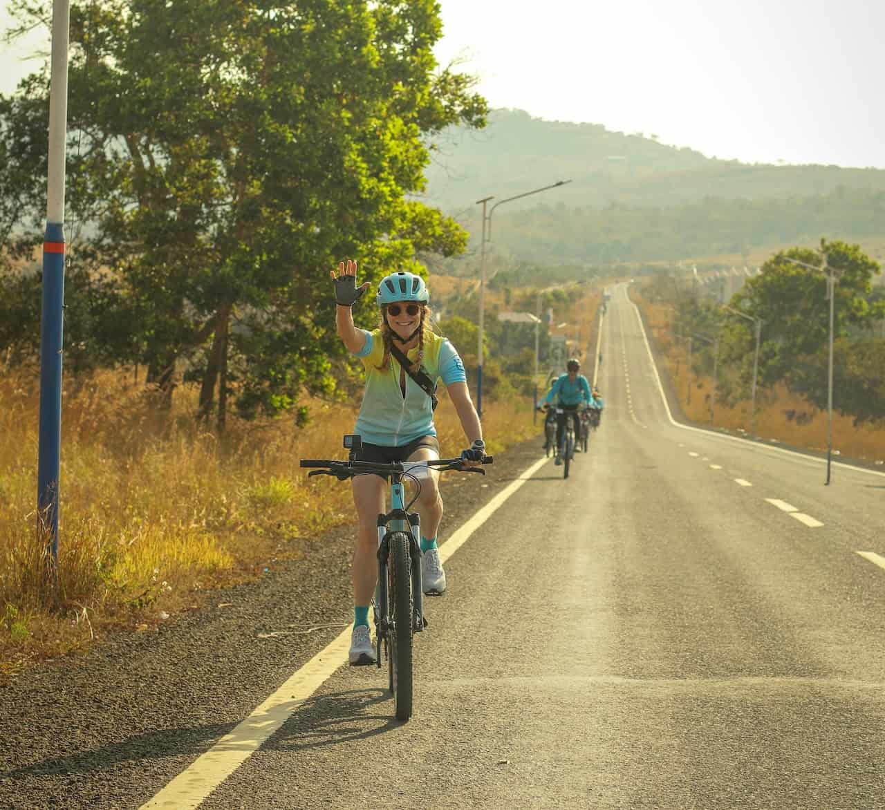 Cyclists riding through the scenic backroads of southern Laos, passing rural villages, Mekong River landscapes, rice fields, and peaceful countryside near Pakse.