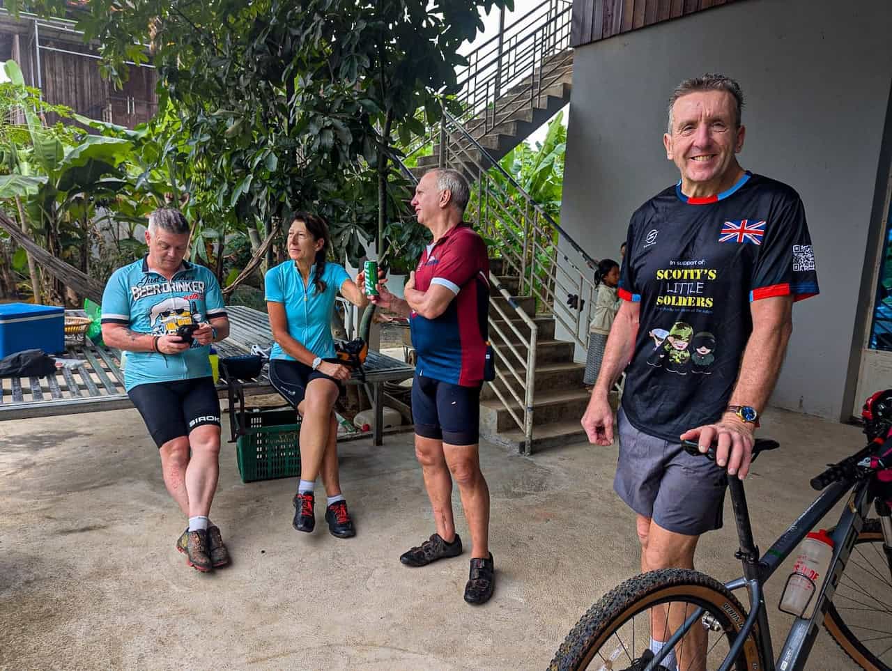 Cyclists riding through a traditional Khmer village near Tonle Sap Lake, passing wooden stilt houses, local farms, rice fields, and authentic Cambodian countryside roads.