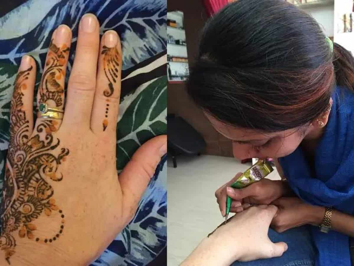 Henna Hand Tattoo in Kochi, Kerala in India Tanya's hennaed hand on the left side of the image and the lady tattoist with black haird and blue shirt on the right.