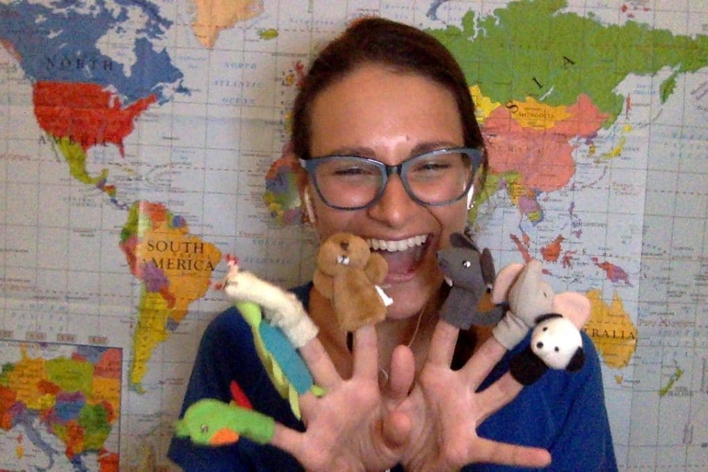 Teaching English Online to Children Teaching English Online to childre. Nicola Rae sitting in front of a wall map smiling with finger puppets.