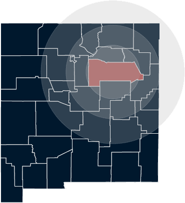Navy blue county map of New Mexico with San Miguel County highlighted in red with area map circles, illustrating Grano Law Offices, P.C.'s areas of service. In general, Grano Law Offices, P.C. serves clients within 75 miles of Las Vegas, NM.