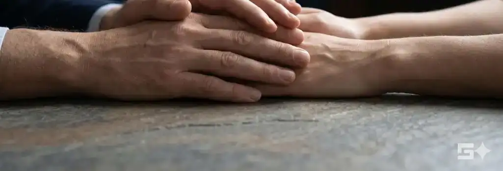 Gentle hands clasped on a slate surface visualize the compassionate guidance and powerful, unyielding legal representation families deserve during a wrongful death claim.