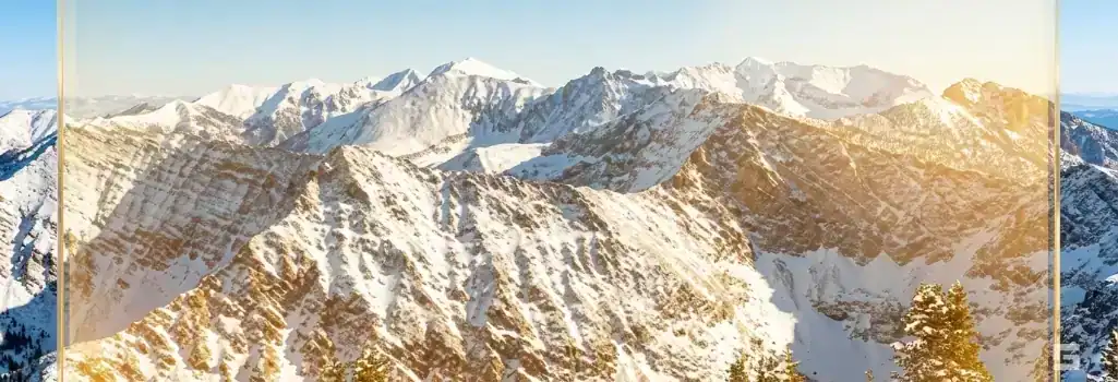 Sunny Northern New Mexico mountains viewed through a premium glass overlay with a warm golden glow, representing ski resort injury claims. Legal strategies by Grano Law Offices, P.C.