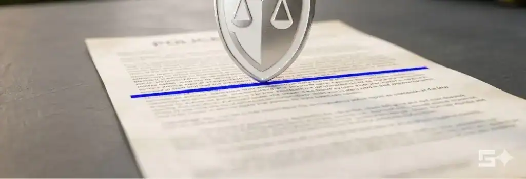 A pristine white and silver legal shield resting on a document with an electric blue strike-through, symbolizing an aggressive defense strategy against DWI charges in New Mexico.