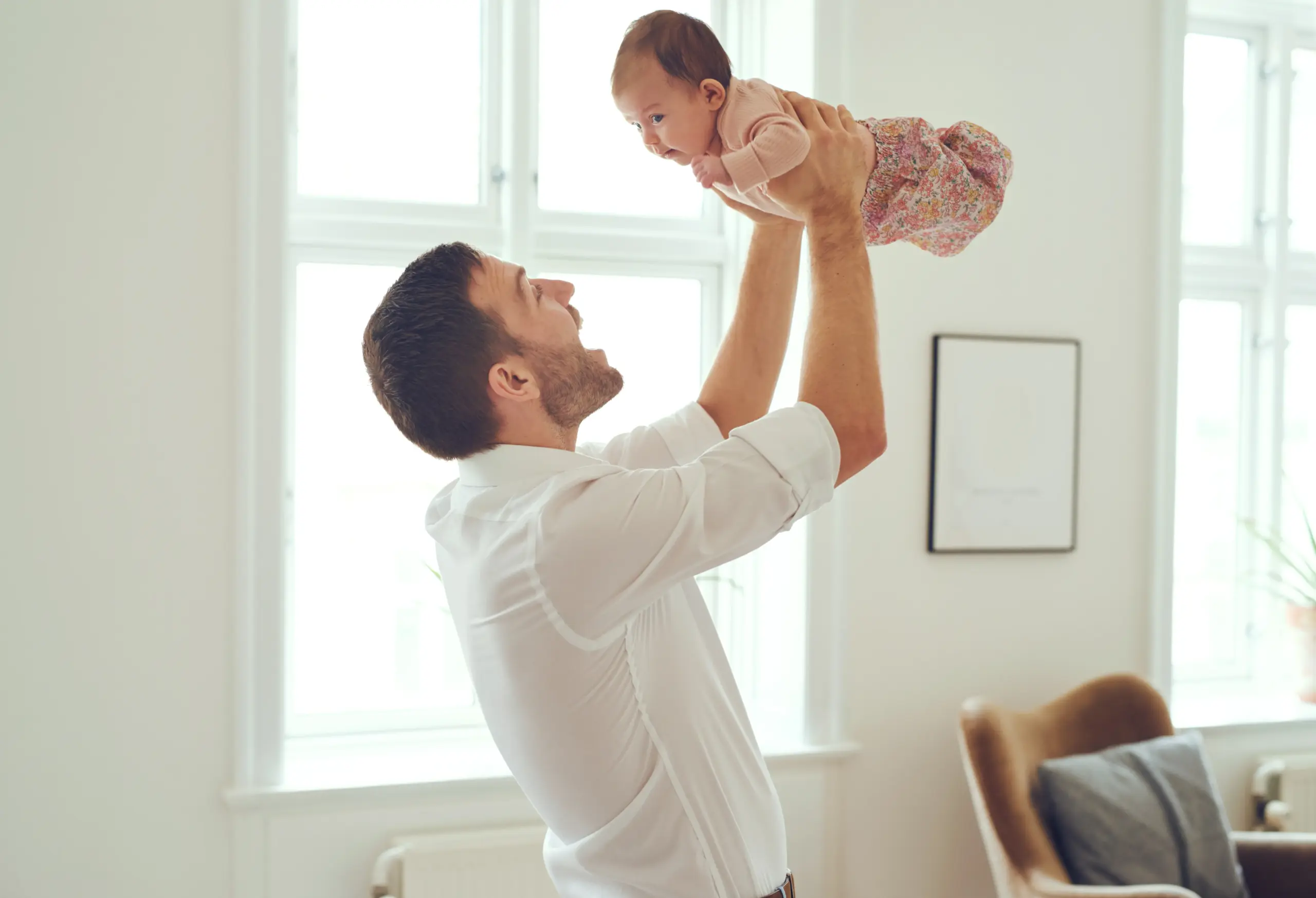 Father holding baby girl above him and smiling at her.