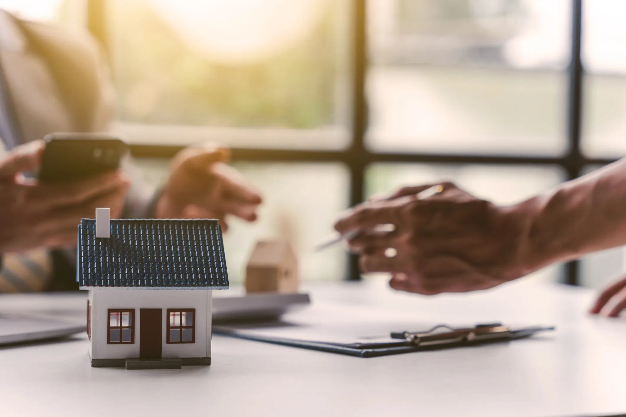 A model house with two poeple discussing paperwork in the background.