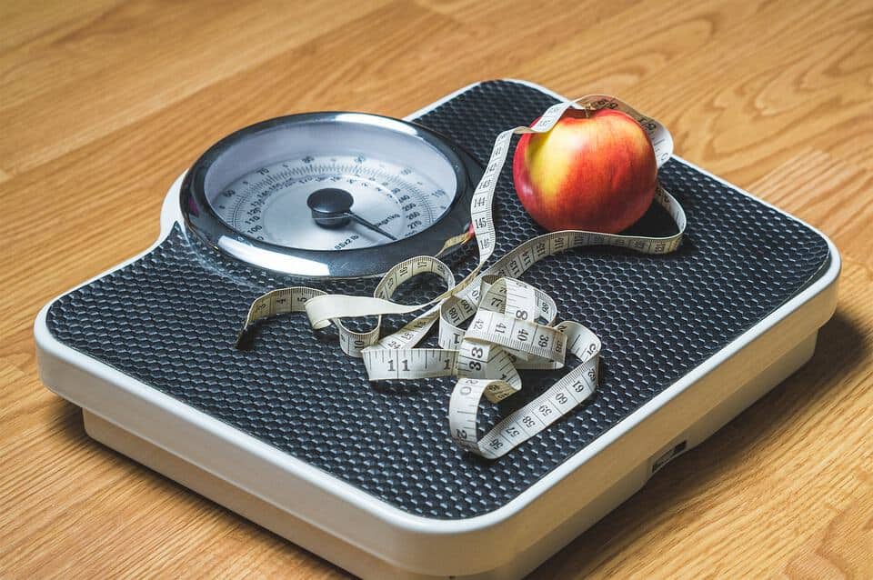 A set of scales with an apple and tape measure