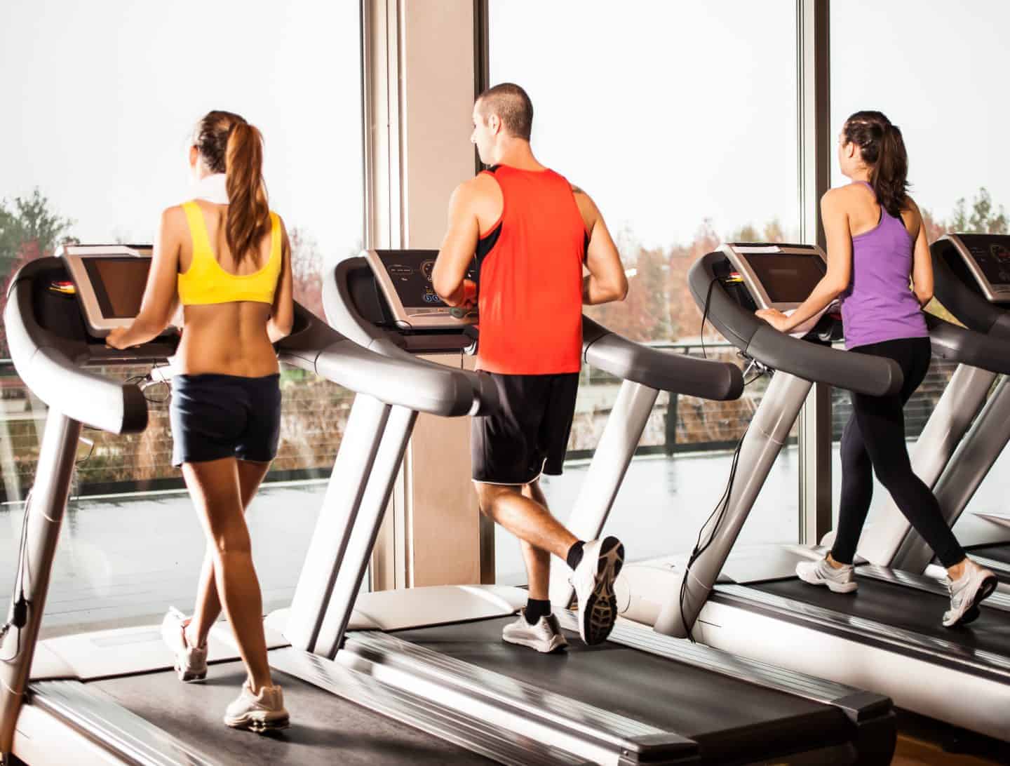 Three people using treadmills in a gym