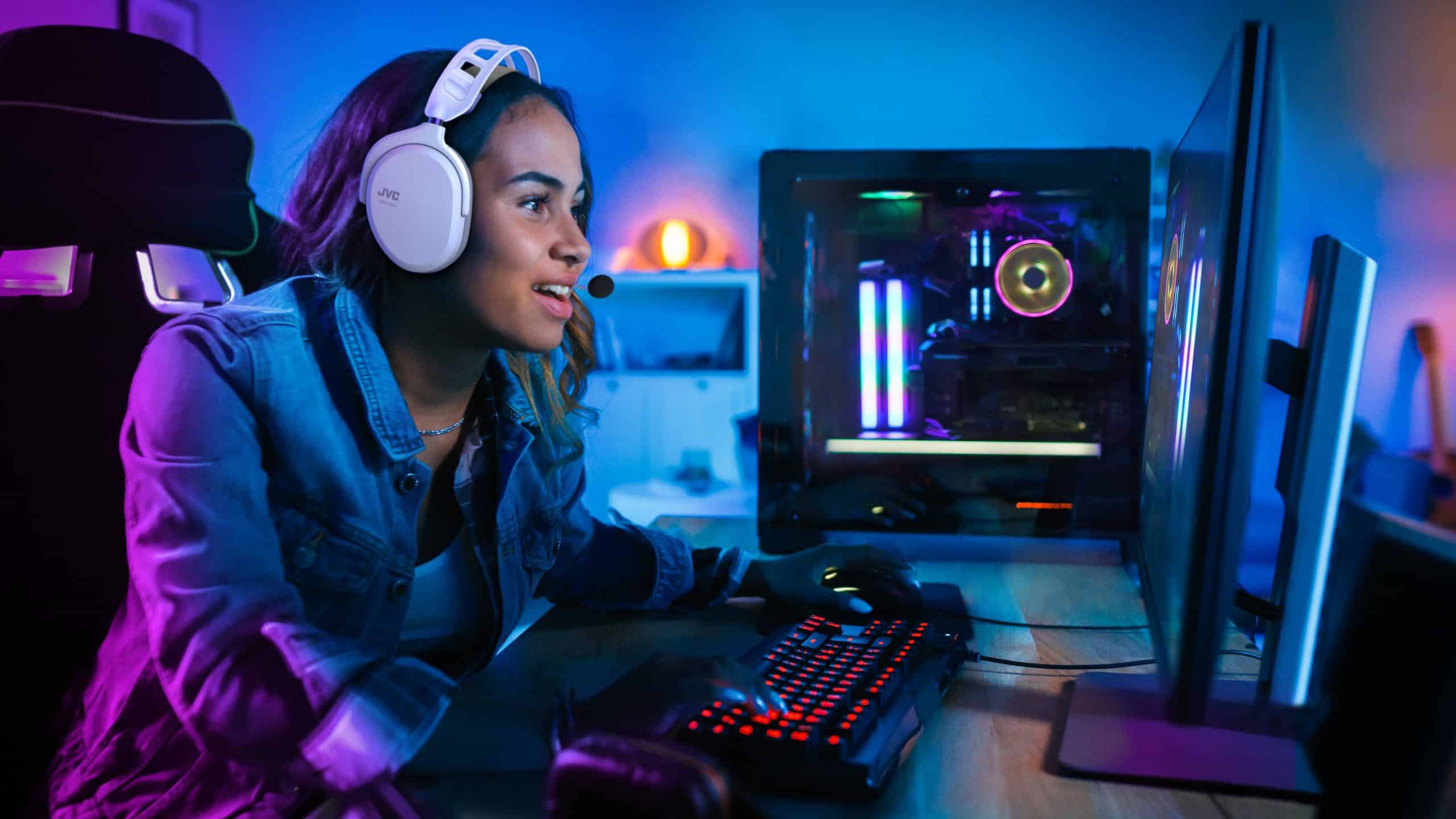 Beautiful and Excited Black Gamer Girl is Playing First-Person Shooter Online Video Game on Her Computer. Room and PC have Colorful Neon Led Lights. Cozy Evening at Home.
