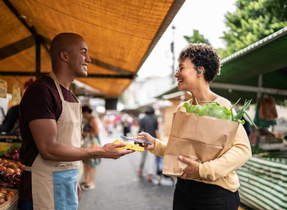 Young woman paying with mobile phone at a street market