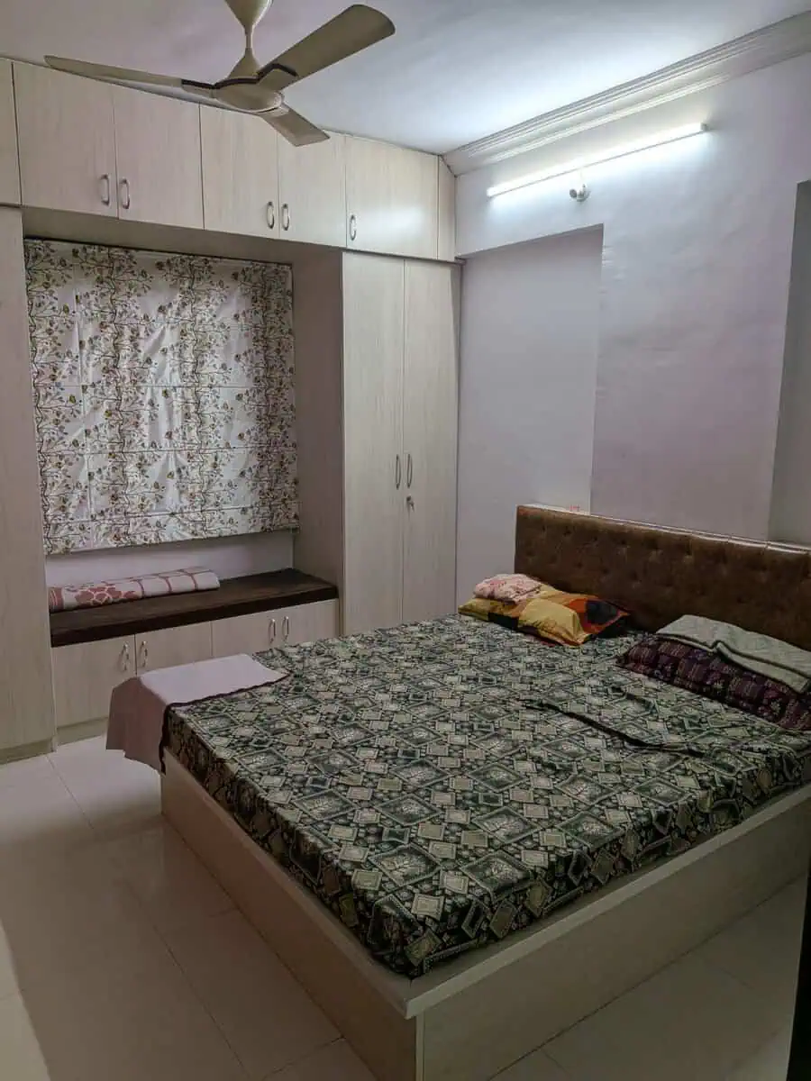 Fully furnished master bedroom with bed, wardrobes and window seat in Estella Wakad
