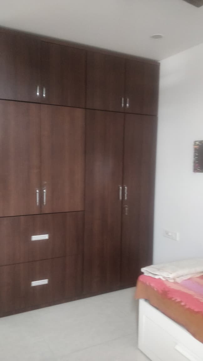 Floor-to-ceiling wardrobes with loft storage in master bedroom of EON Homes Hinjewadi 2 BHK