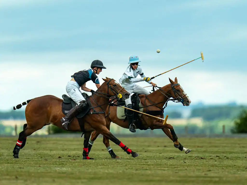 Wilf Bate lifting the polo ball into the air at speed in the elite polo at the Stonehenge Polo Festival