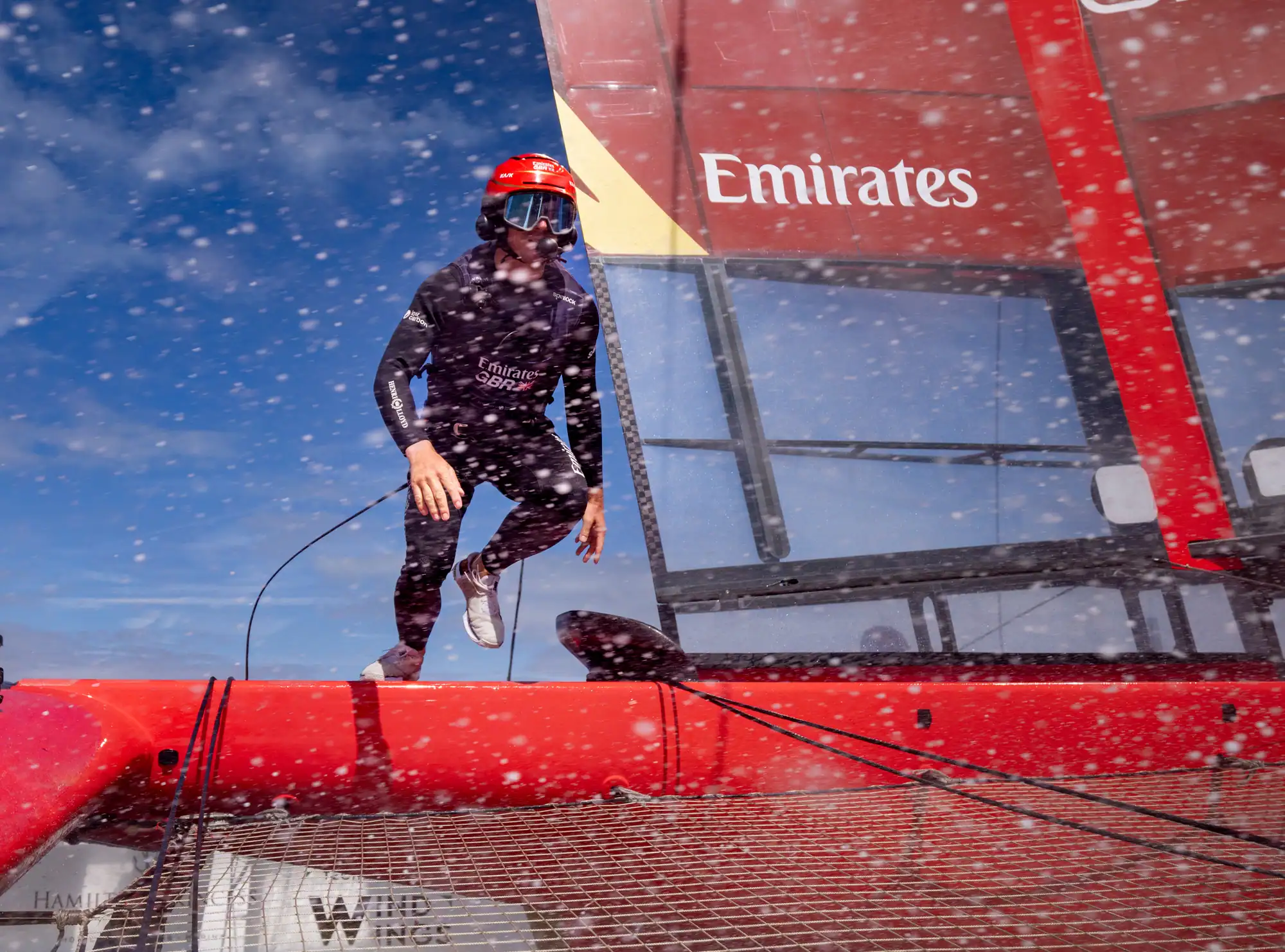 Emirates crew member leaping across the foiling F50 at the SailGP racing in Portsmouth
