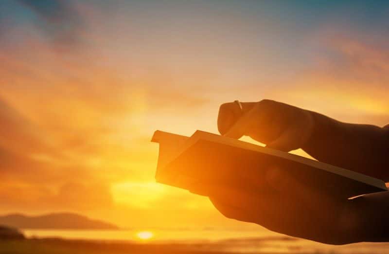 Mãos sobre uma Bíblia à luz do pôr do sol, ilustrando a leitura sobre a verdade de Deus