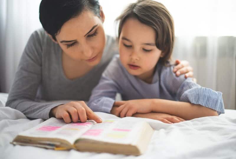 Mãe e filha lendo juntas, em um momento de ensino sobre o amor de Deus
