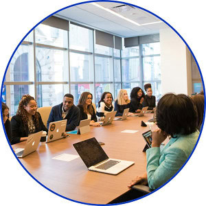 People sat around a board room table with laptops