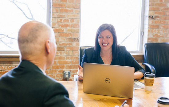 Two people sat at a table with a laptop