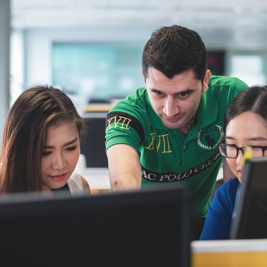 Three people looking at a computer